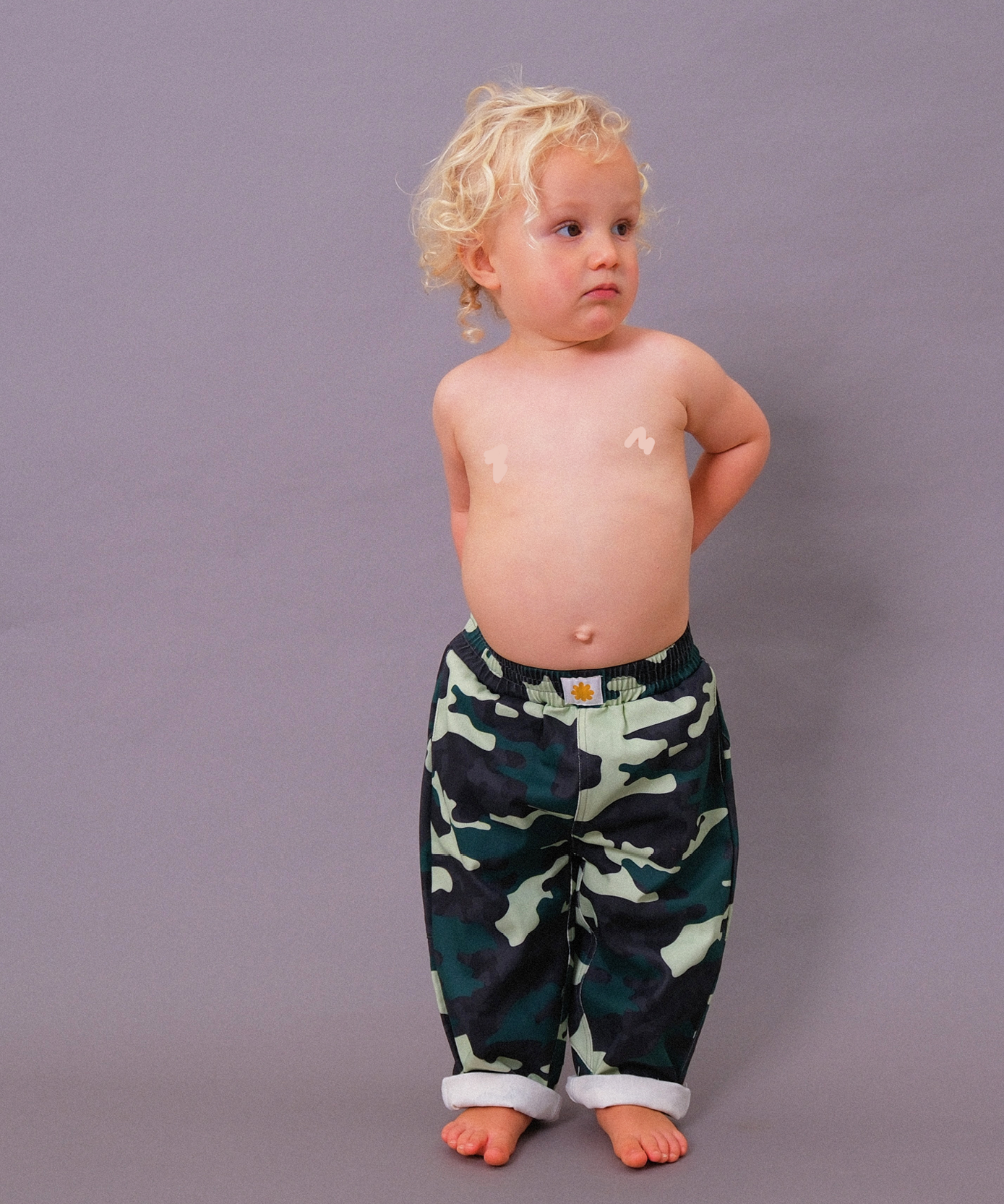 Sonny Label Circus26 camo print kids piece flat lay on a grey background.