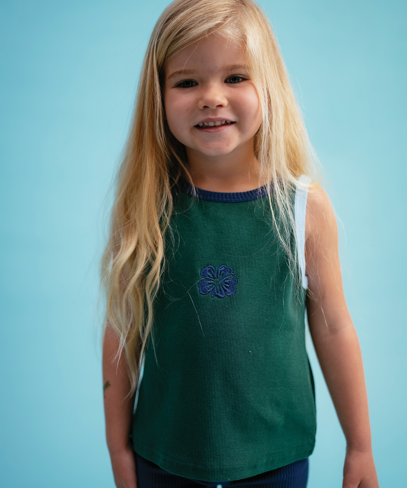 Child in Sonny Label Summer25 collection piece on a vivid sky blue background.