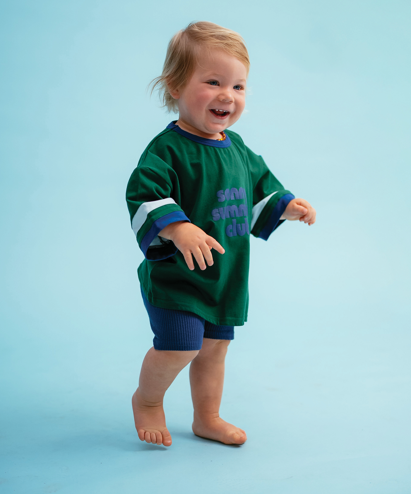 Child in Sonny Label Summer25 collection pieces on a vivid sky blue background.
