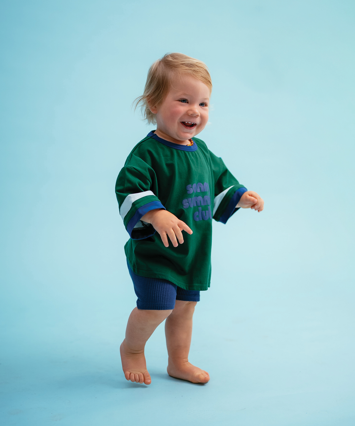 Child in Sonny Label Summer25 collection piece on a sky blue background.