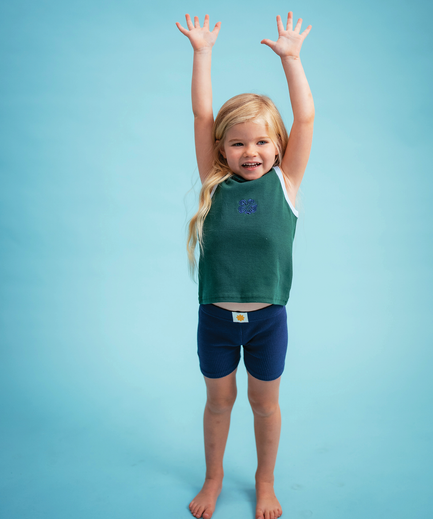 Child wearing Sonny Label Summer25 playsuit on a sky blue background.