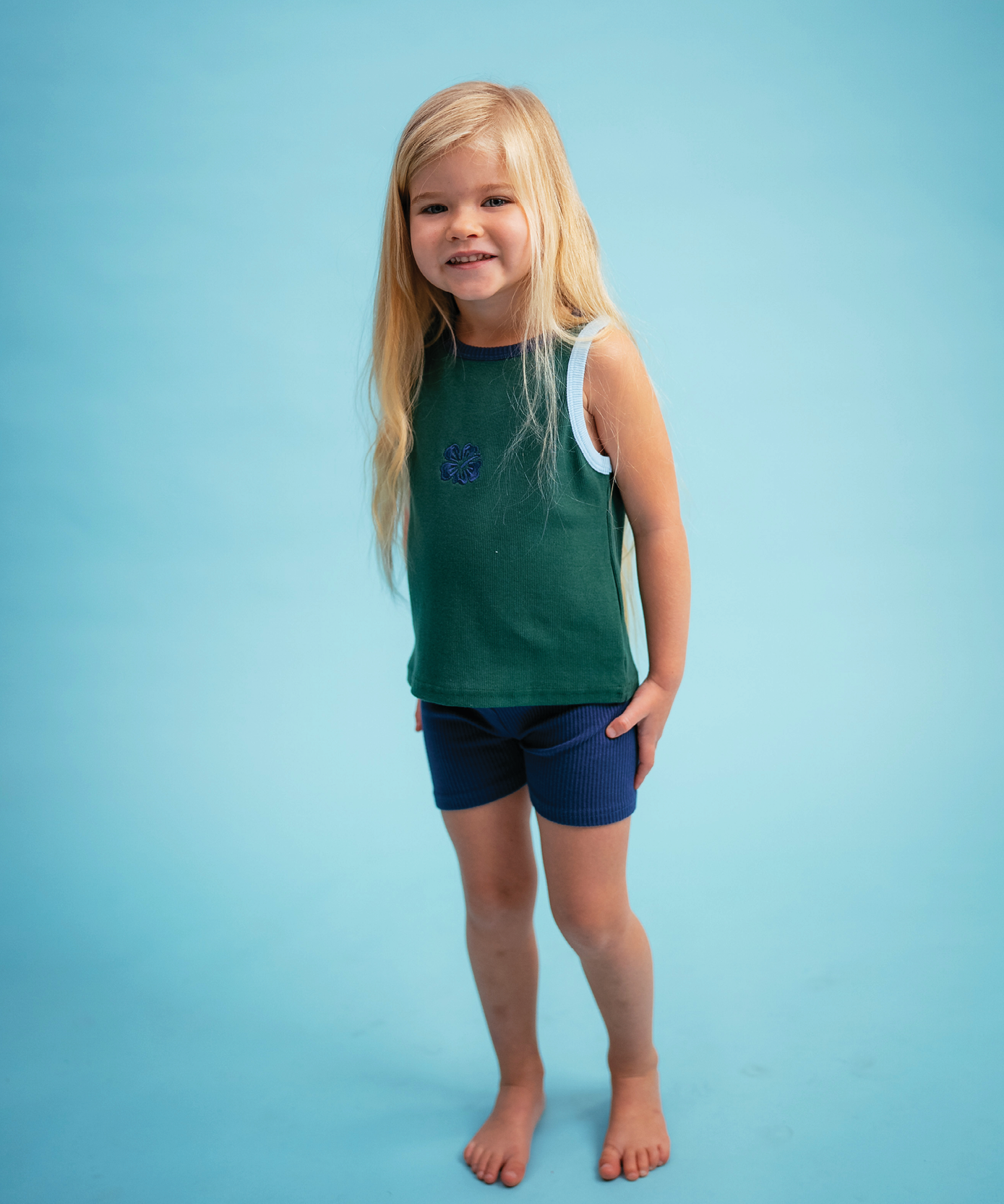 Child in Sonny Label Summer25 collection piece on a sky blue background.