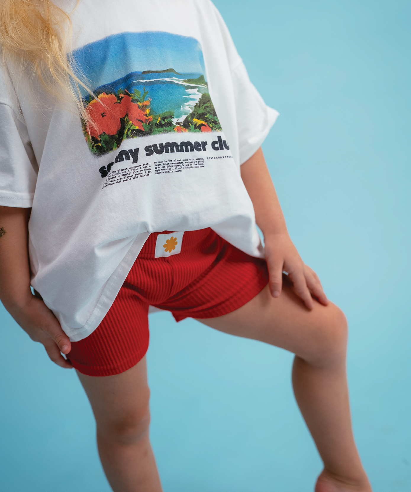 Child wearing Sonny Label Summer25 knitted shorties on a vivid sky blue background.