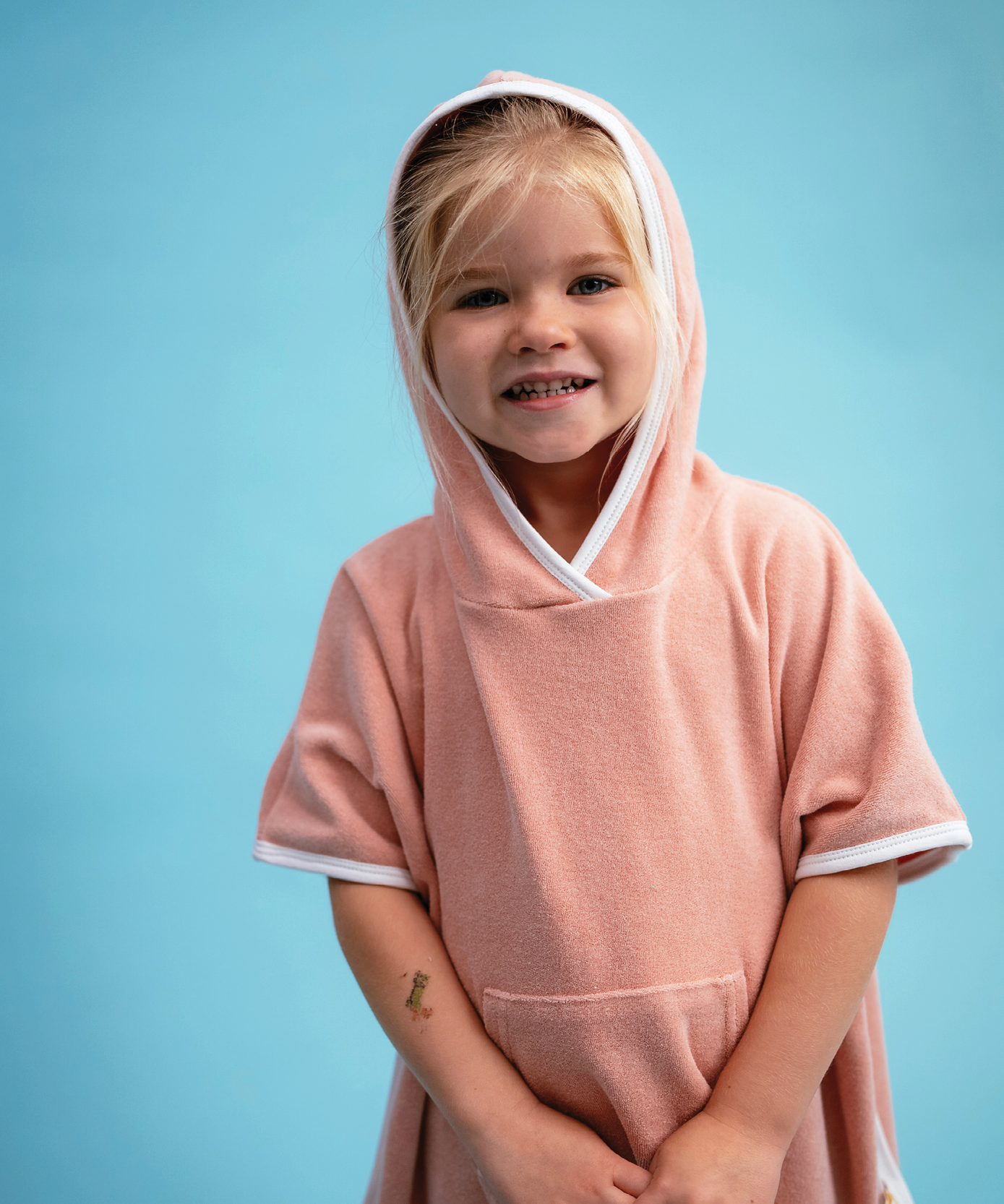 Child wearing Sonny Label Summer25 playsuit on a sky blue background.