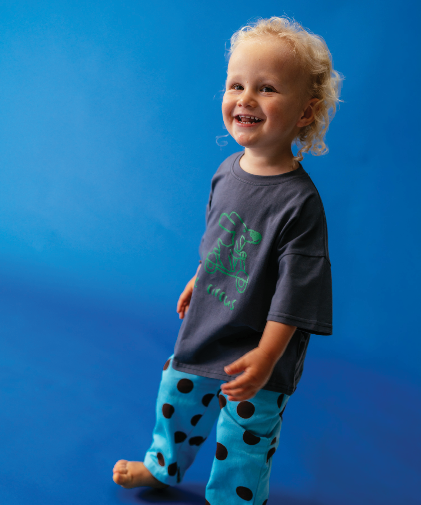 Child wearing Sonny Label Circus26 sport pants and long-sleeve tee on a deep blue background.