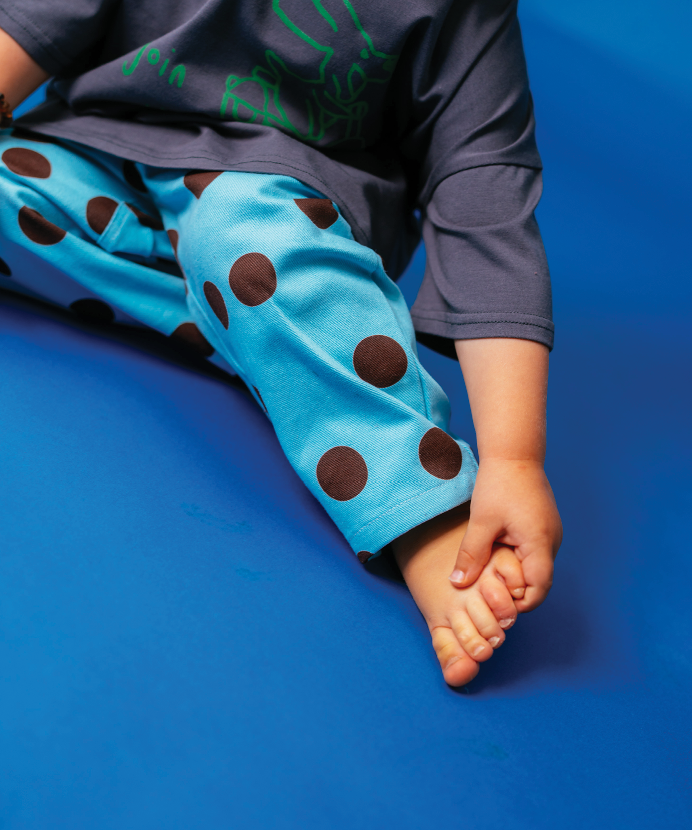 Child in Sonny Label Circus26 everyday tee and beanie styled on a vivid blue backdrop.