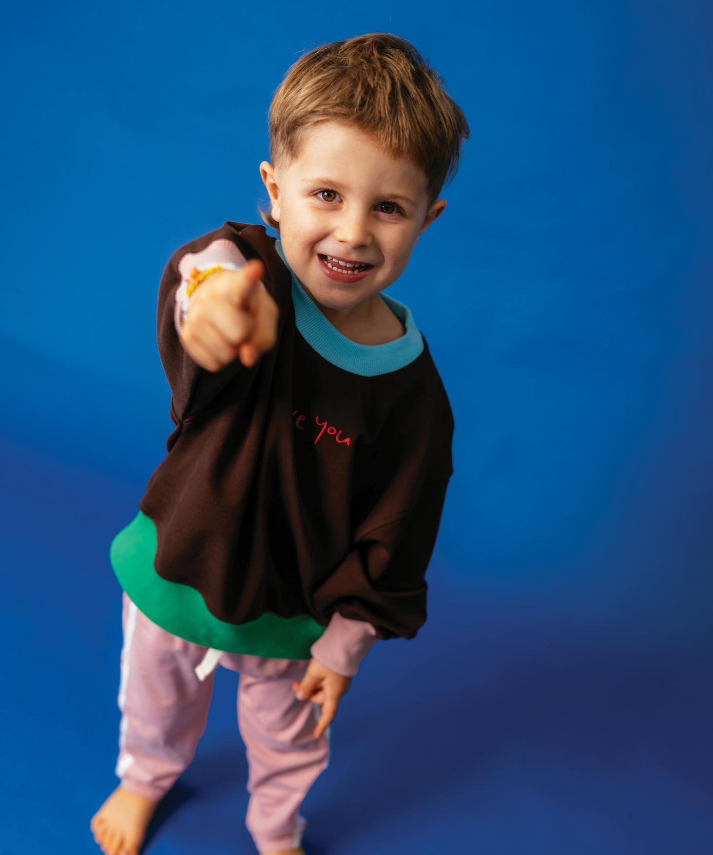 Child in Sonny Label Circus26 sloppy joe sweatshirt on a deep blue studio background.