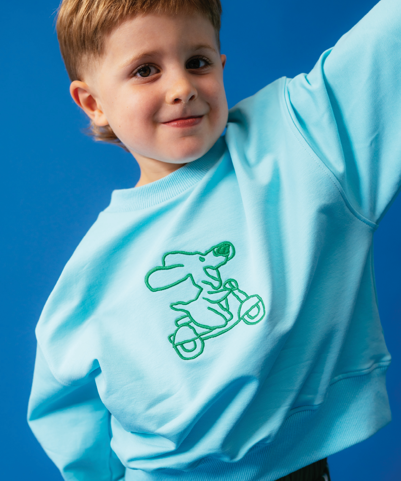 Child wearing Sonny Label Circus26 colourful outfit on vivid blue backdrop. Variant upload.