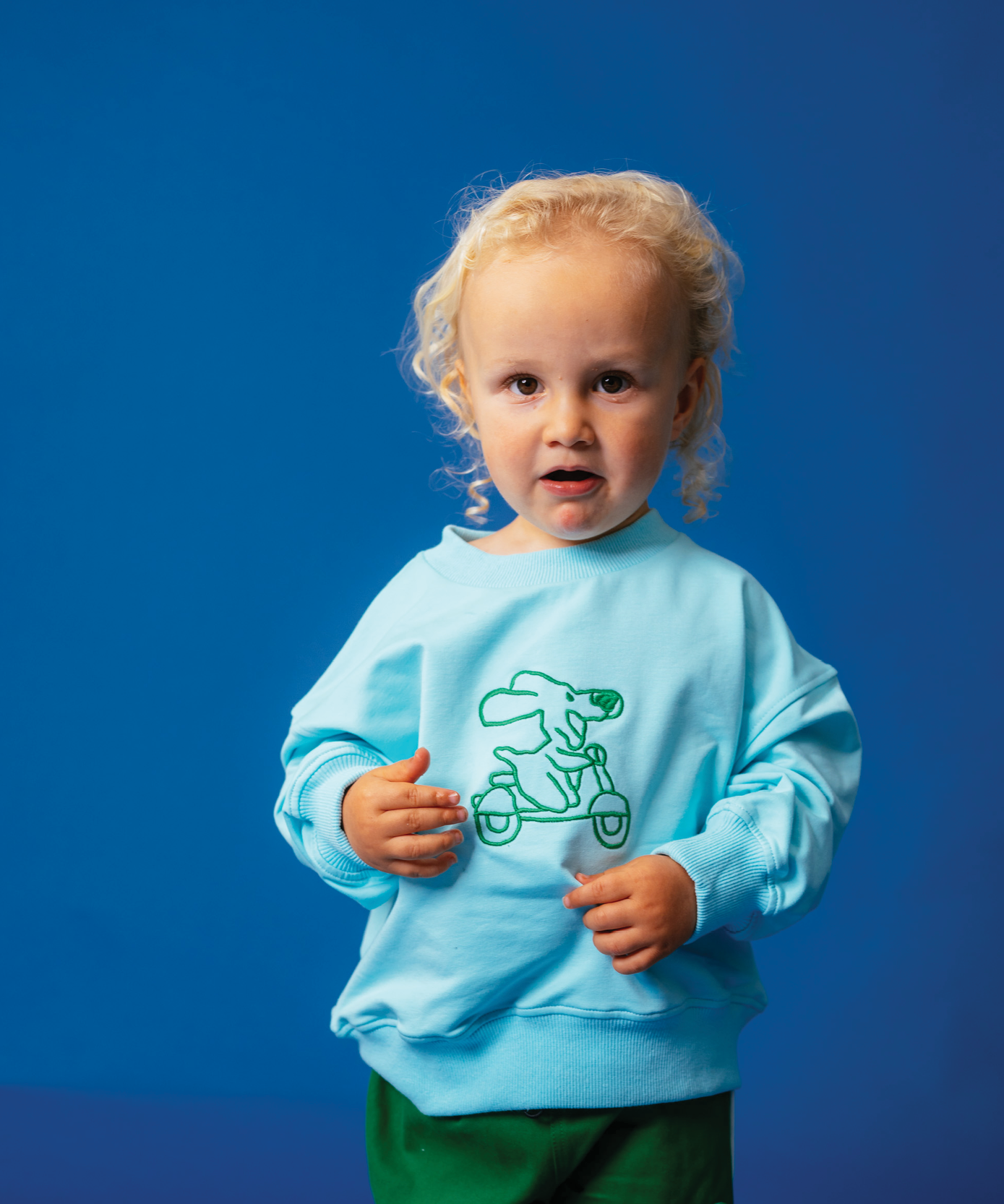 Child in Sonny Label Circus26 kids outfit on a vivid blue studio background. Variant upload.
