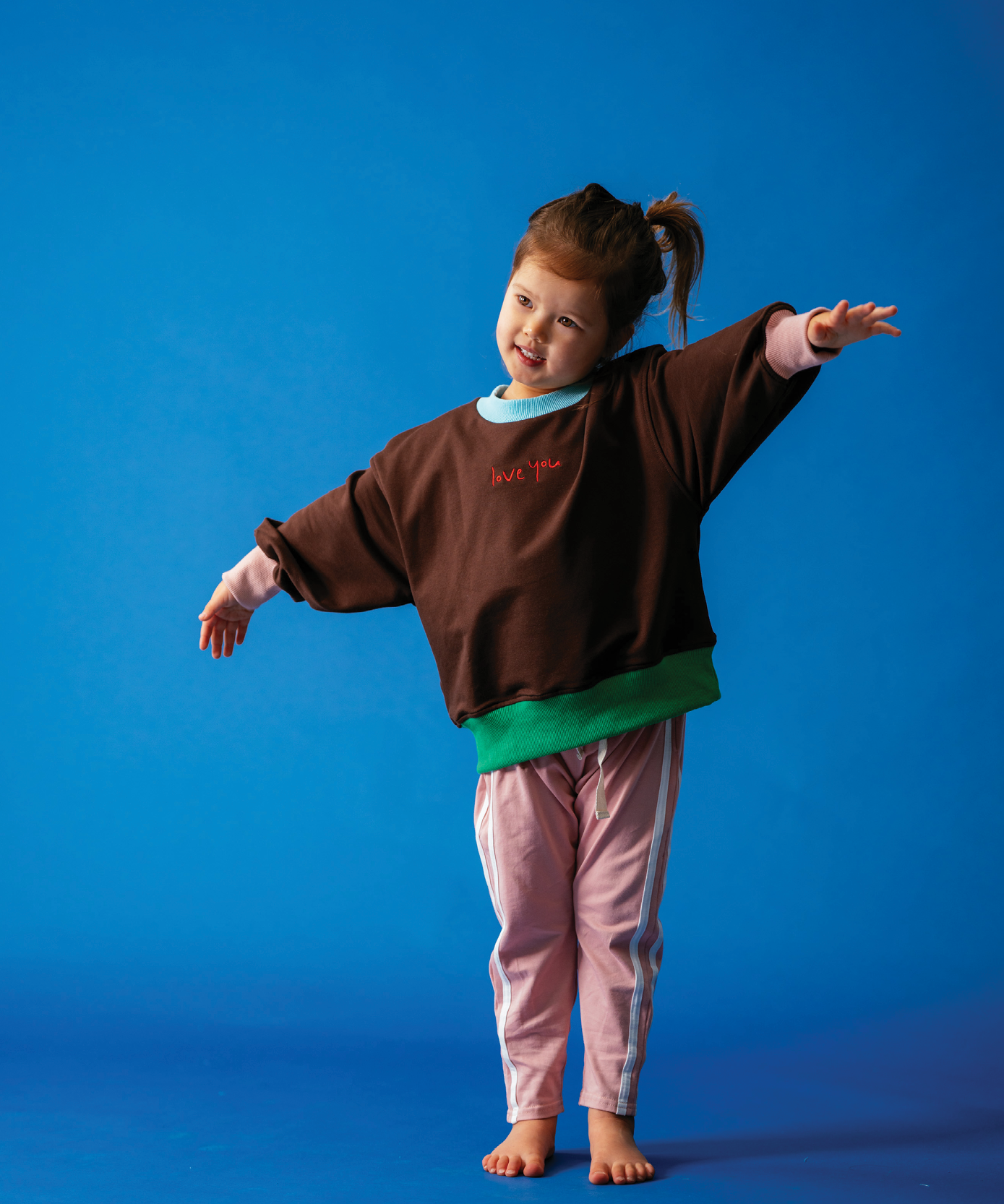 Child in Sonny Label Circus26 collection pieces on a vivid blue background.
