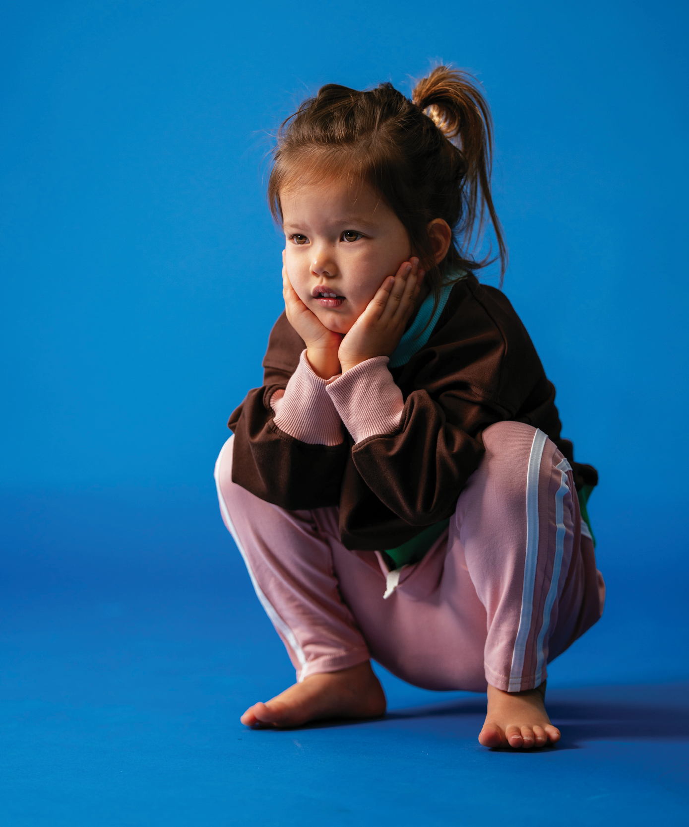 Child in Sonny Label Circus26 stripe long-sleeve tee and pants on a vivid blue background.