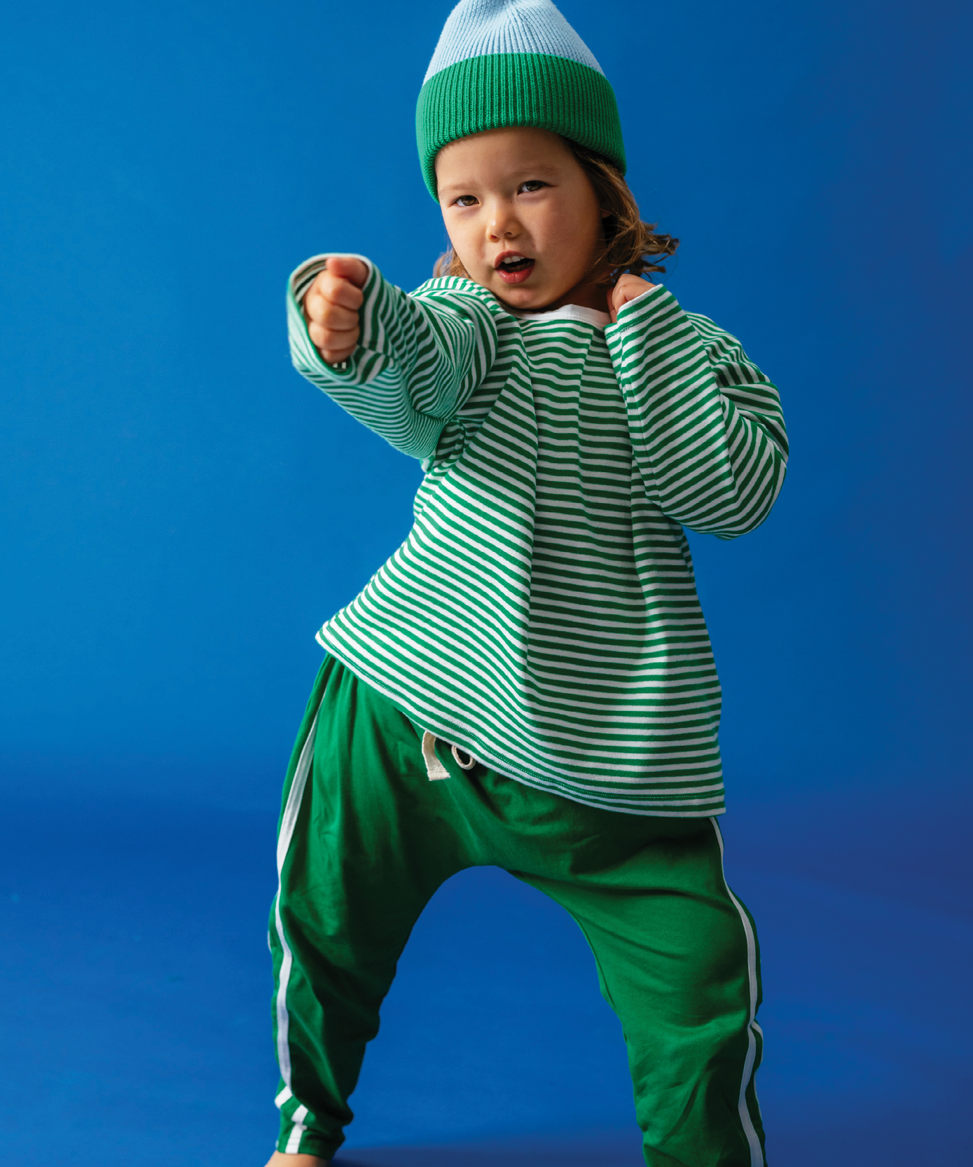 Child in Sonny Label Circus26 sloppy joe and slouch pants on a vivid blue studio background.