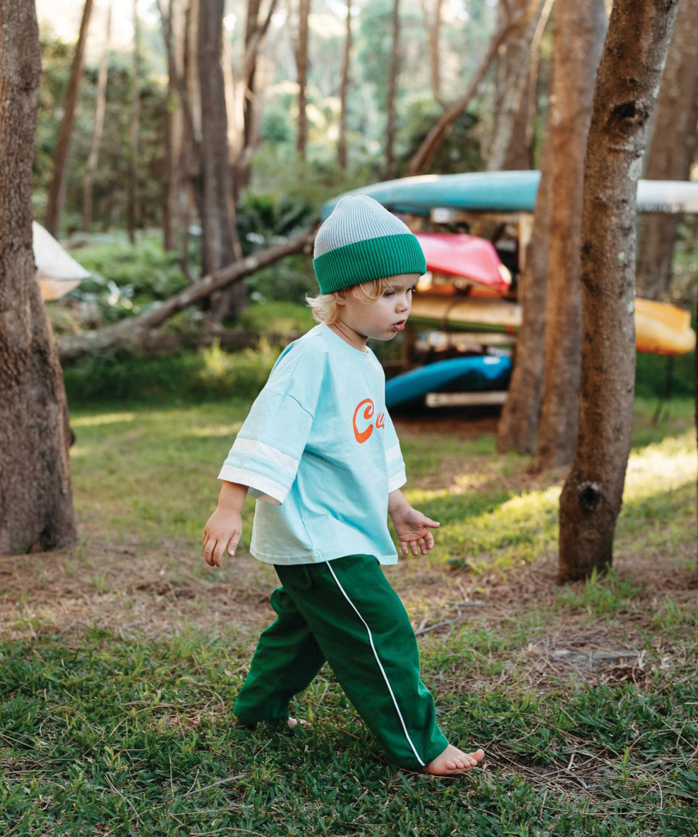 Child wearing Sonny Label Circus26 sport tee and pants in a playful pose on a deep blue backdrop.
