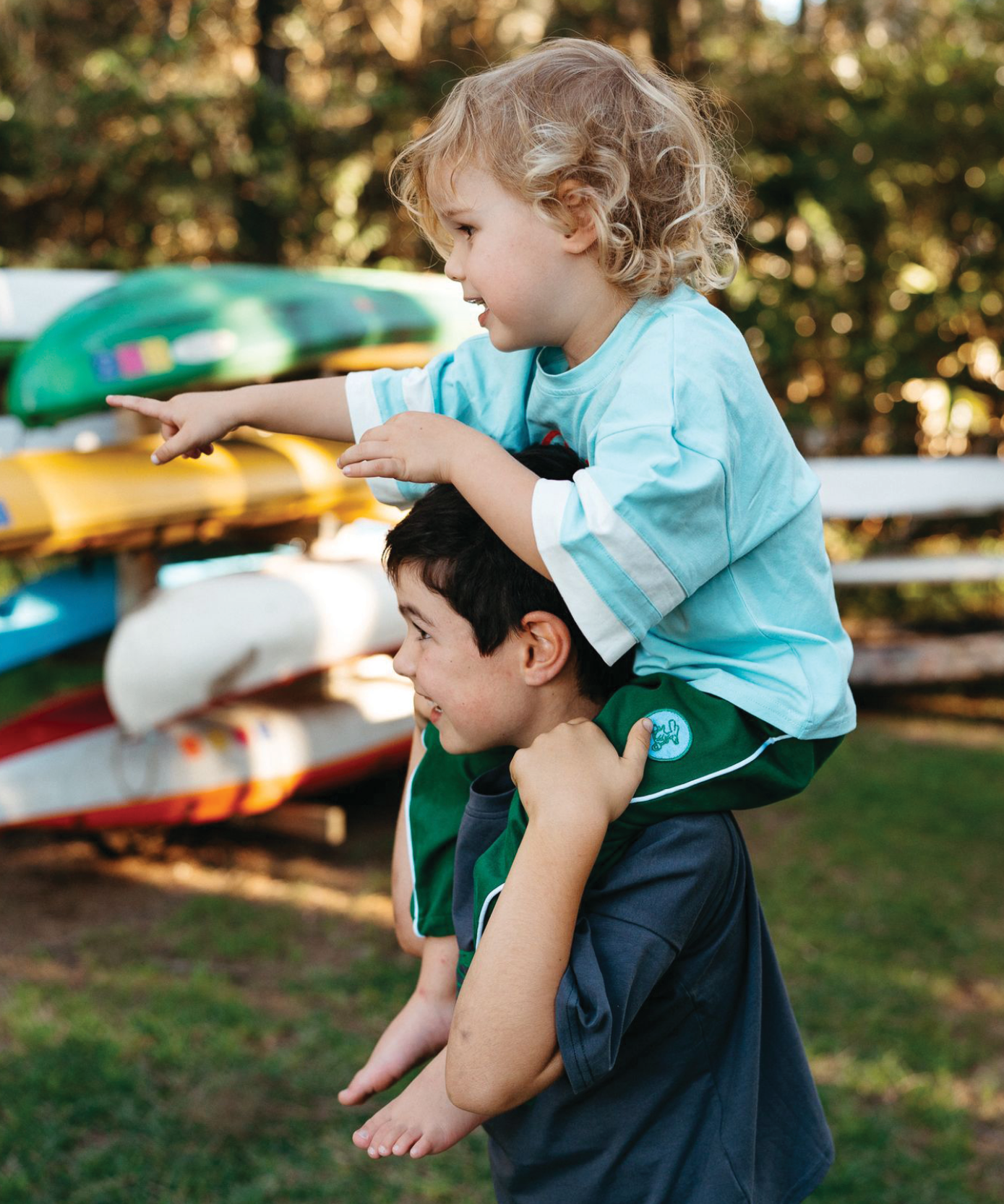 Child in Sonny Label Circus26 green stripe long-sleeve tee and beanie on a vivid blue background.
