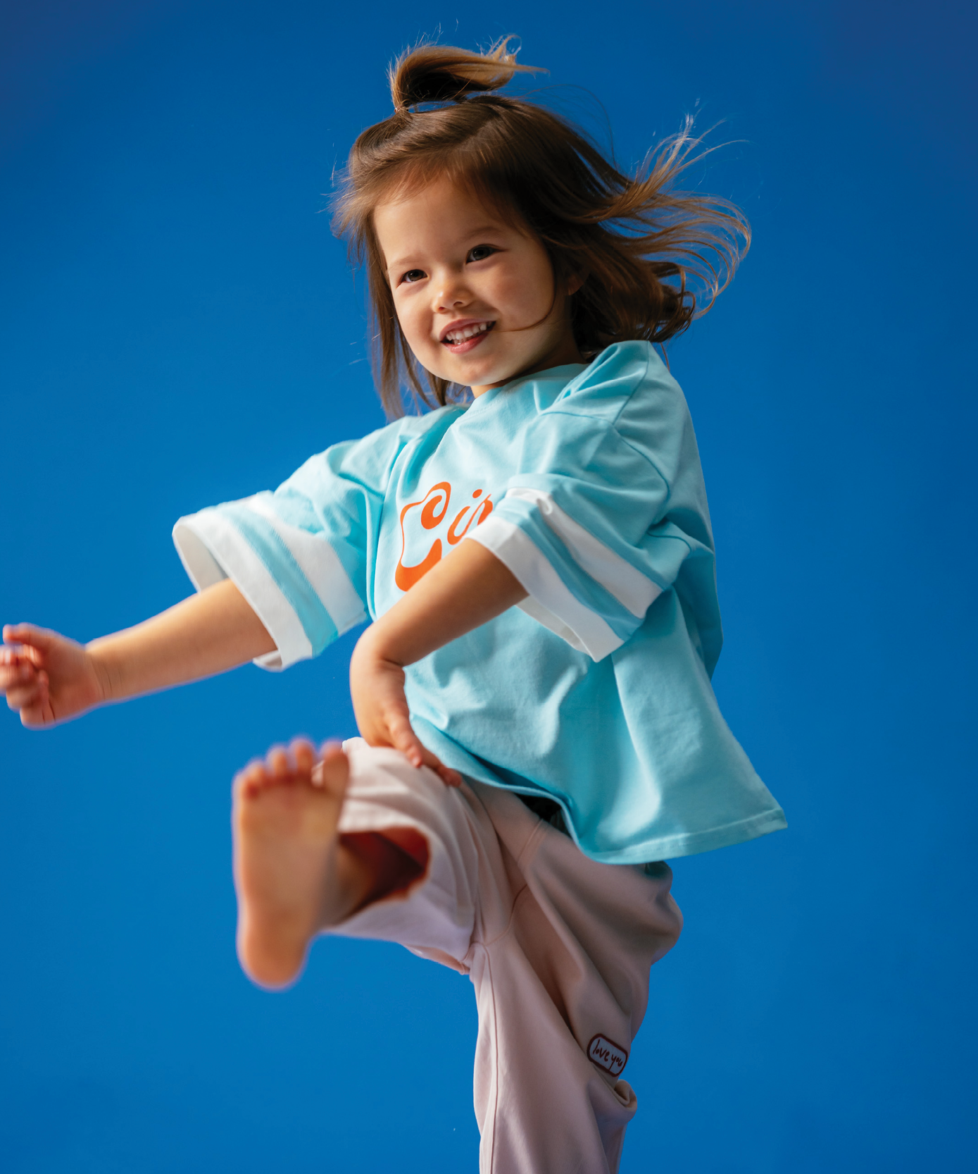 Child in Sonny Label Circus26 sloppy joe and slouch pants on a vivid blue background.