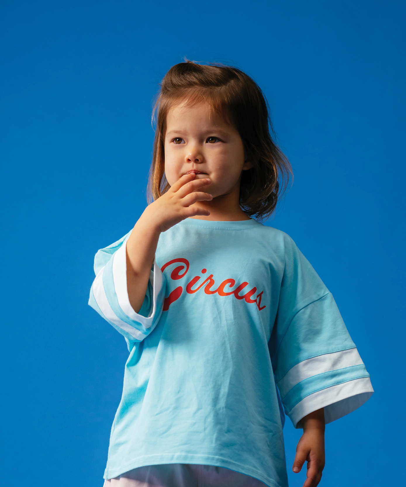 Child wearing Sonny Label Circus26 retro sweatshirt and sport pants on a deep blue backdrop.