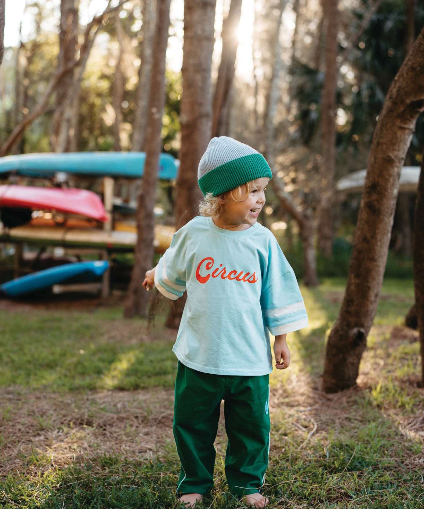 Child wearing Sonny Label Circus26 everyday tee and beanie on a vivid blue background.