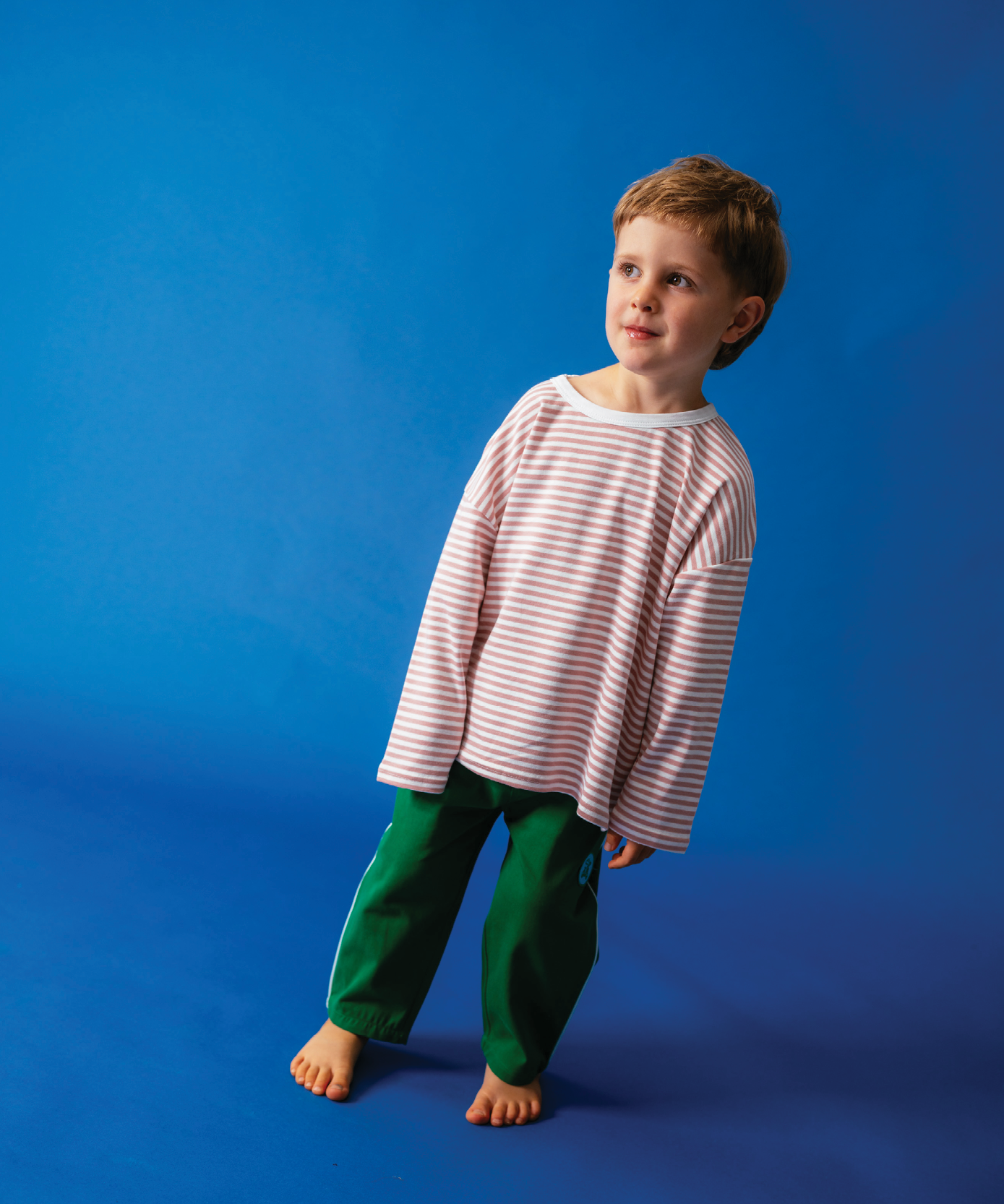 Child in Sonny Label Circus26 colourful outfit on a deep blue studio background.