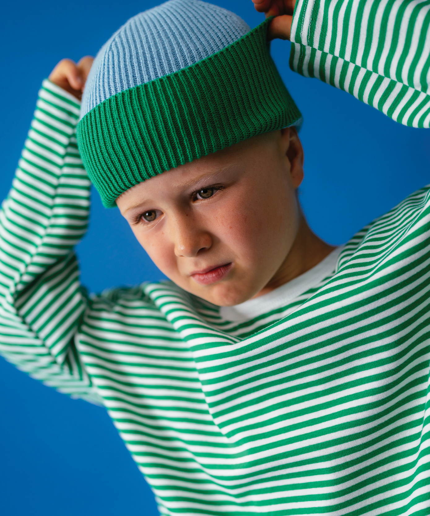 Child in Sonny Label Circus26 polka dot pocket pants on a vivid blue studio background.