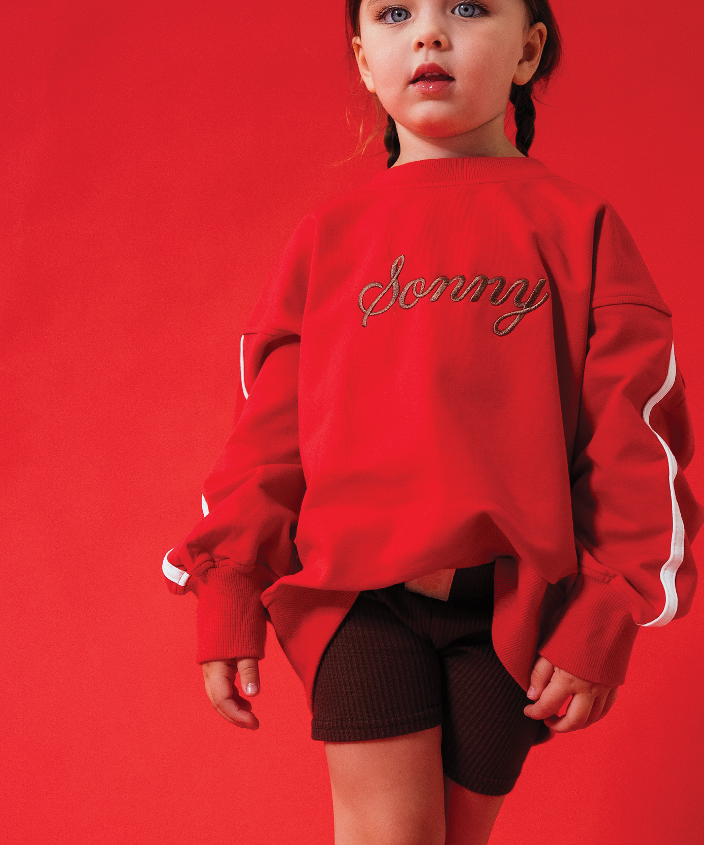 Child wearing Sonny Label LOVER collection pieces on a light grey studio backdrop.