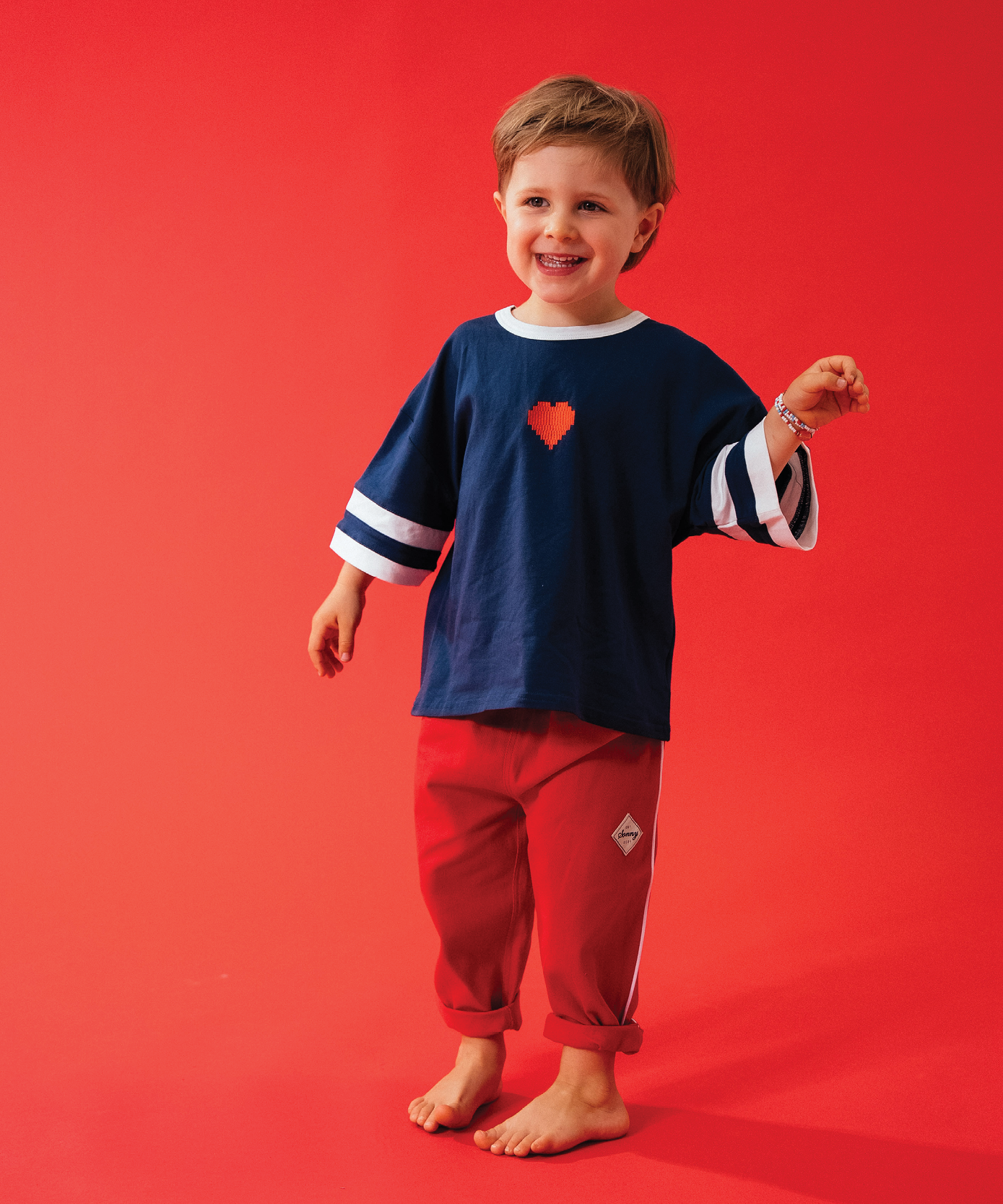 Child in Sonny Label LOVER red zip-through jacket and shorts on a light grey background.