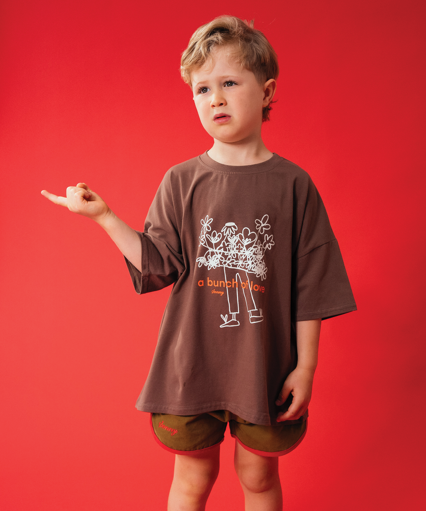 Child in Sonny Label LOVER collection red zip jacket on a soft white background.