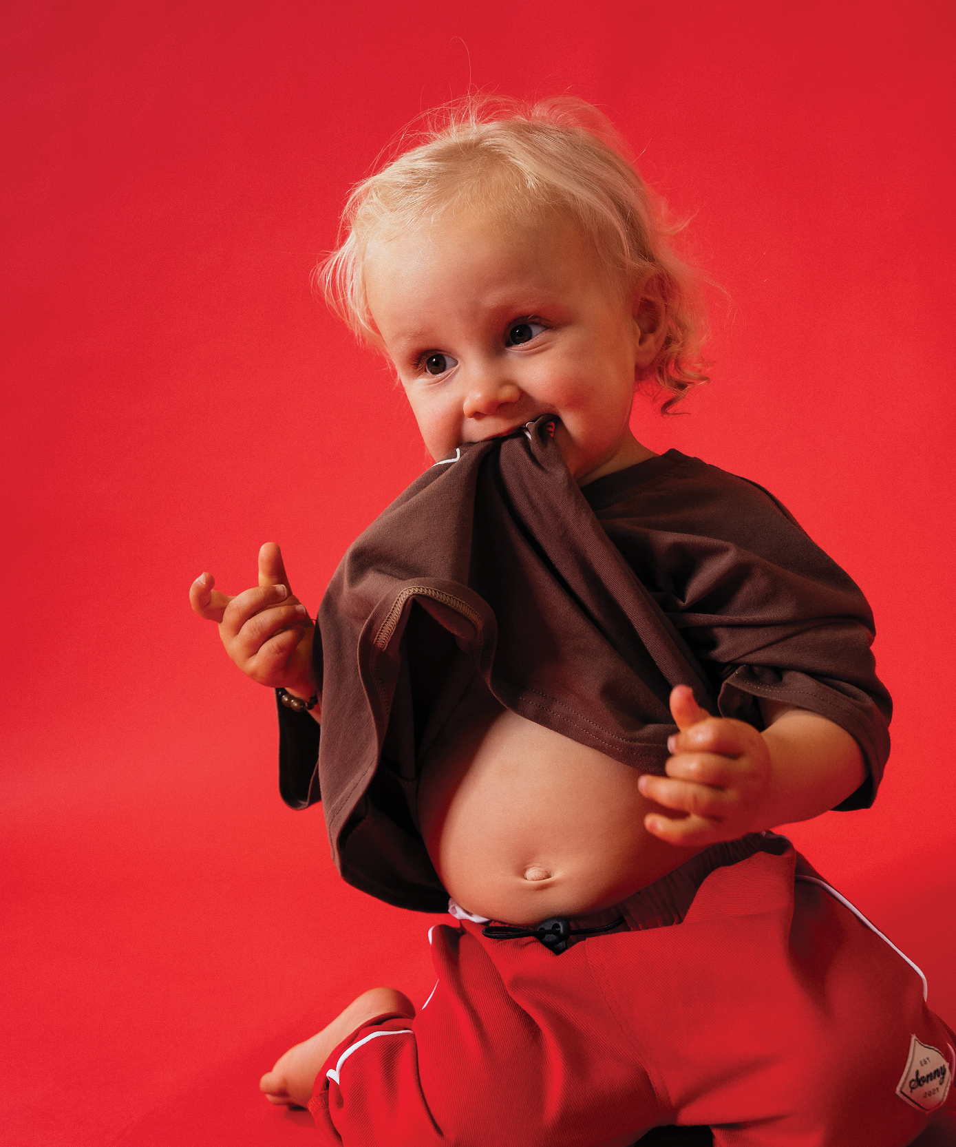 Child wearing Sonny Label LOVER collection khaki shorts with Sonny embroidery on a light grey background.